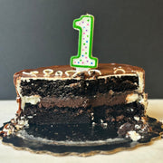 Chocolate fudge cake sliced in half with a 1 number candle on top